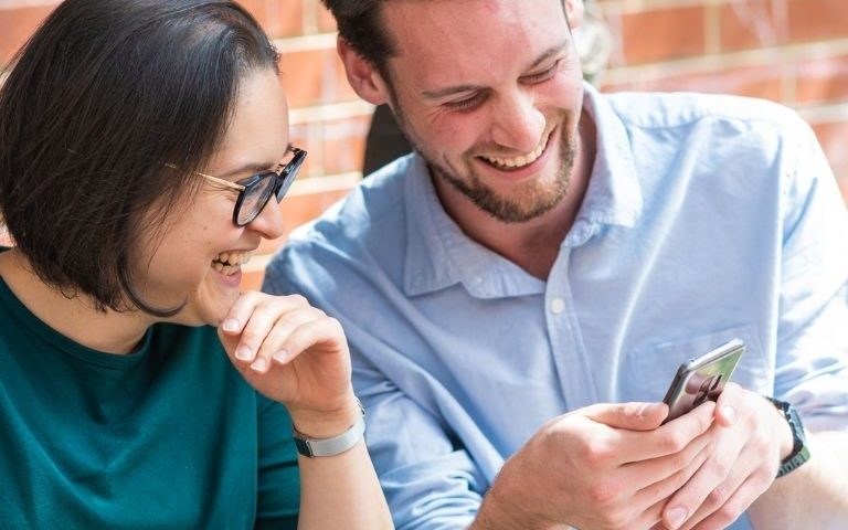 man and women looking at a mobile phone and laughing